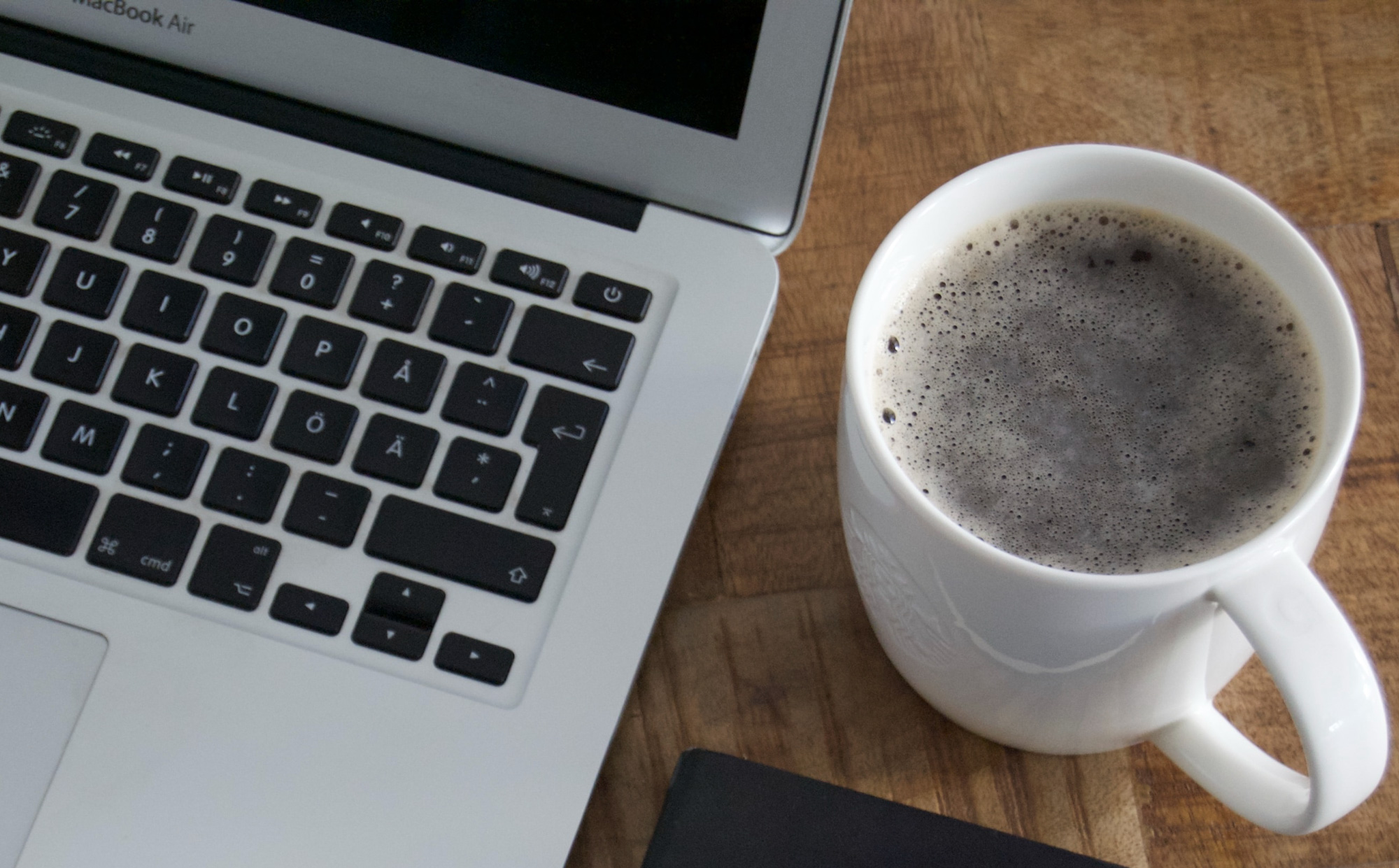 Laptop på skrivbord med kaffekopp bredvid